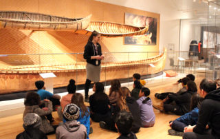 Royal Ontario Museum's Hack the ROM program. Indigenous student group with presenter in front of birchbark canoes